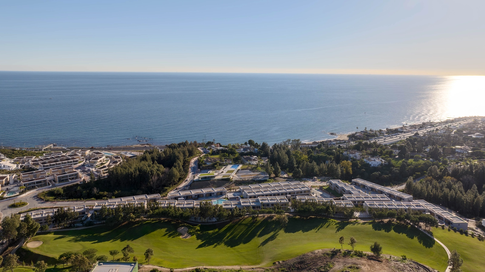 Et luftfoto af Evergreen Homes, perfekt beliggende mellem golfbanens grønne fairways og det blå Middelhav.