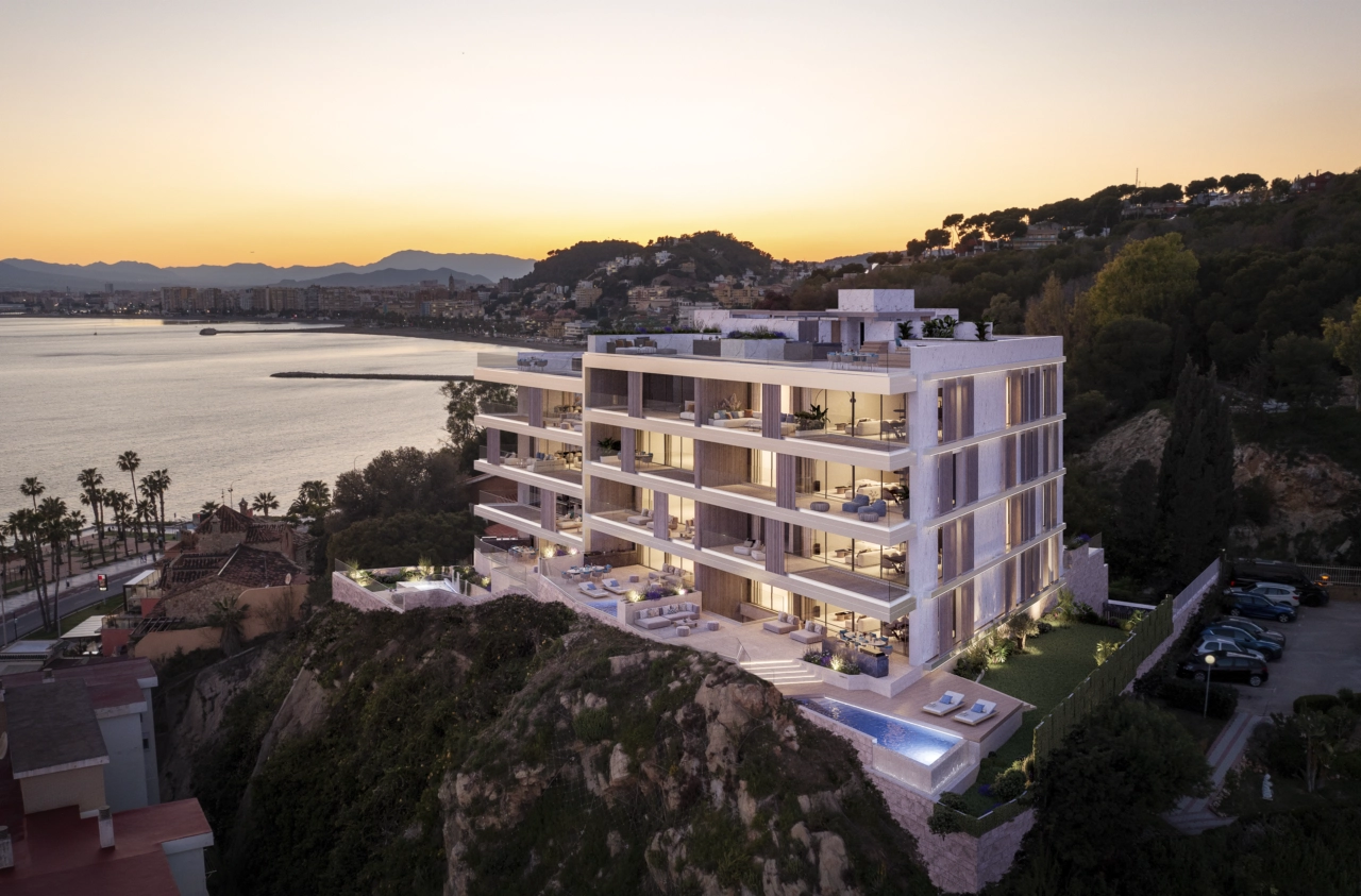 Bebyggelsens moderne arkitektur er smukt oplyst ved solnedgang, med udsigt over Malagas kystlinje.