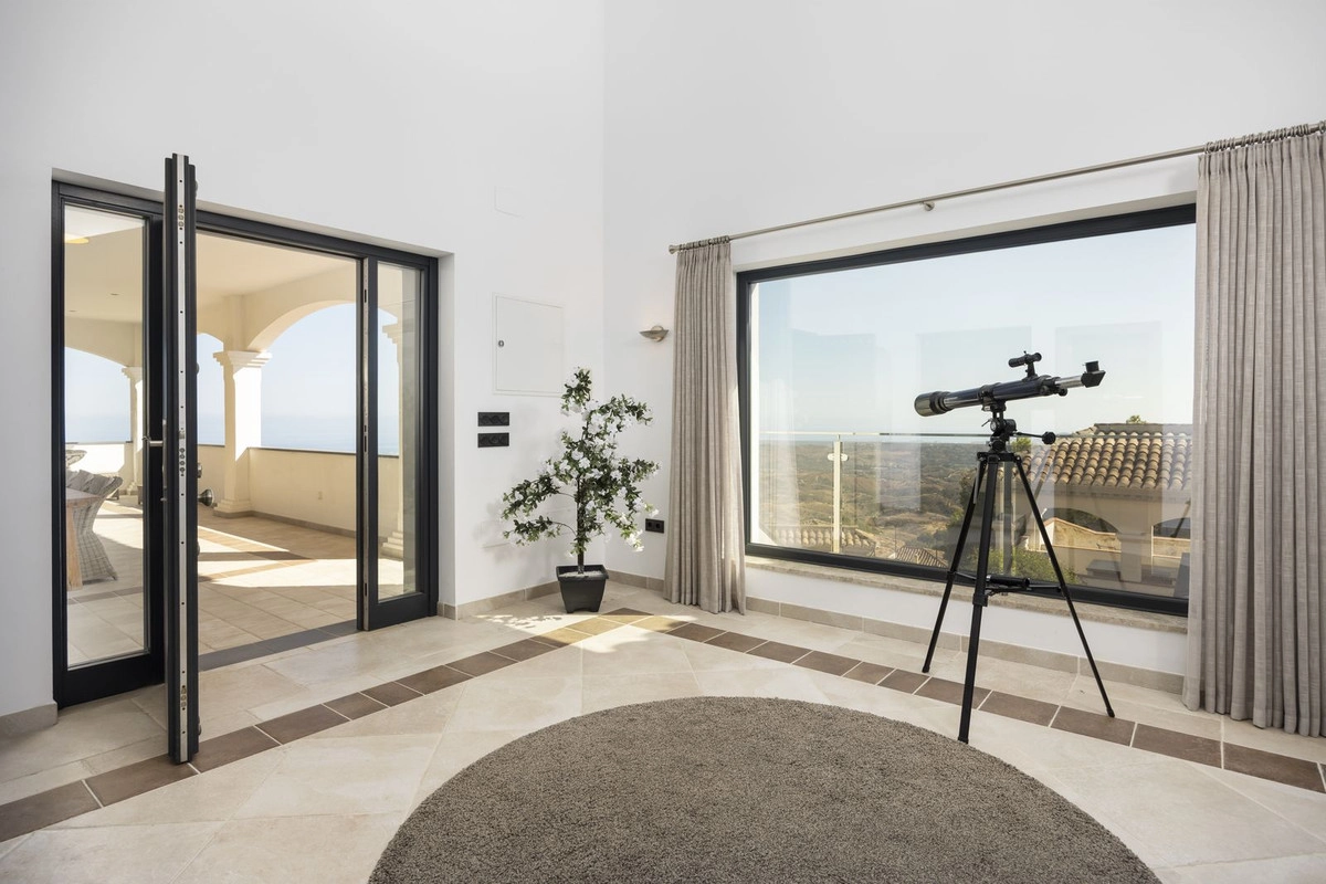 Et fredfyldt hjørne af hjemmet, hvor store vinduer indrammer det spektakulære landskab, og døre åbner ud til terrassen.