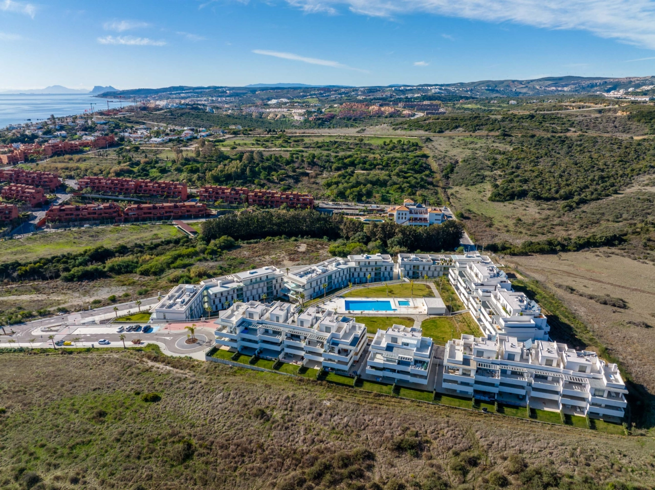 Den centrale swimmingpool og solbadningsområde, omgivet af anlagte haver, skaber en privat oase for beboerne.